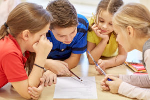 A group of elementary students working together to fill out a worksheet