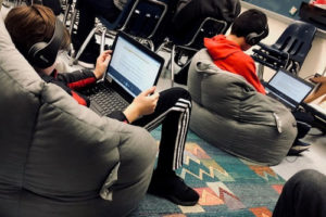 A boy in a beanbag chair reading along to an audiobook.