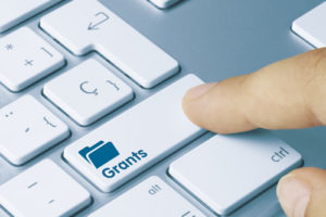 A person taps a keyboard key labeled "grants" in search of unique education grants.