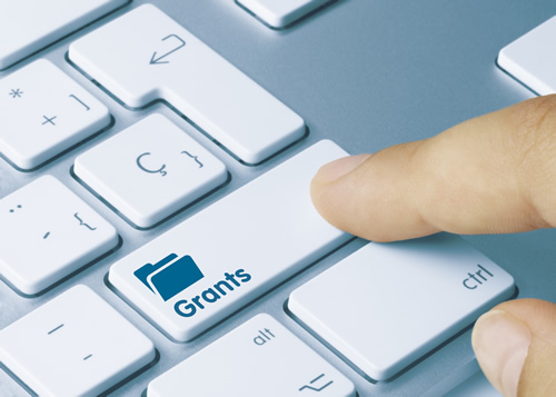 A person taps a keyboard key labeled "grants" in search of unique education grants.