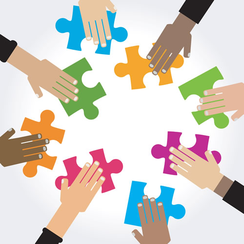 different-colored hands doing a puzzle with assorted colored pieces