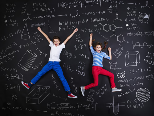 Two students jumping up and down on a blackboard with math problems