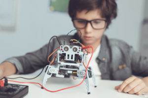A student sits in front of a robot in a K-12 robotics and programming class.