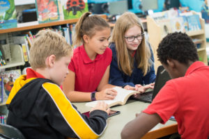 This group of students is reading at the library to avoid the summer slide.